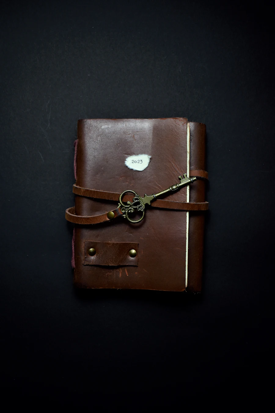 Carnet relié en cuir brun fermé par une clé, posé sur un plan de travail