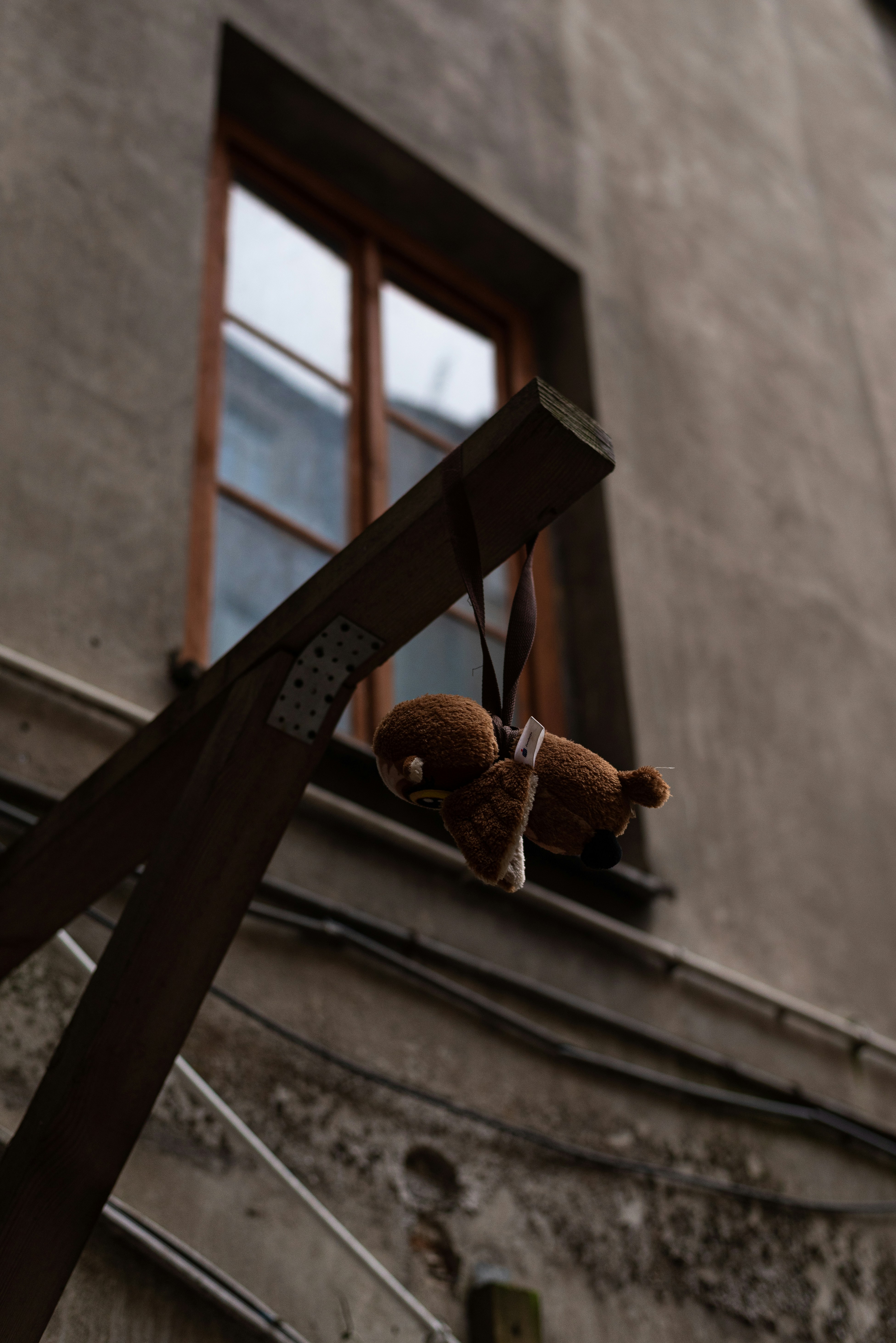 a teddy bear hanging from a wooden cross