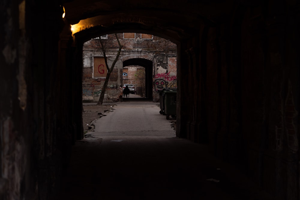 a dark tunnel with a person sitting on a bench