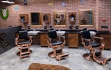 a barber shop with a brick wall and lots of chairs