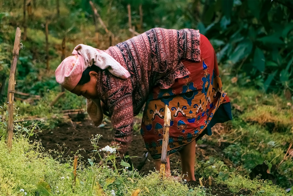 a woman in a colorful dress is digging in the dirt