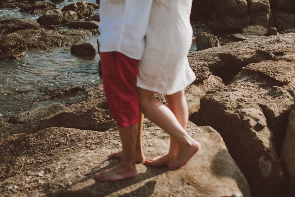 a couple of people standing on top of a rocky beach