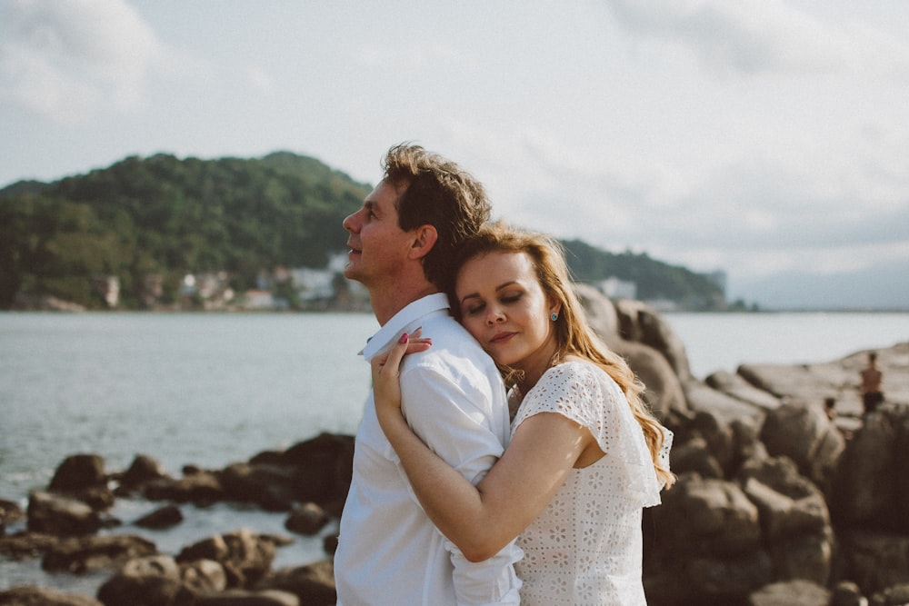 a man and a woman standing next to a body of water