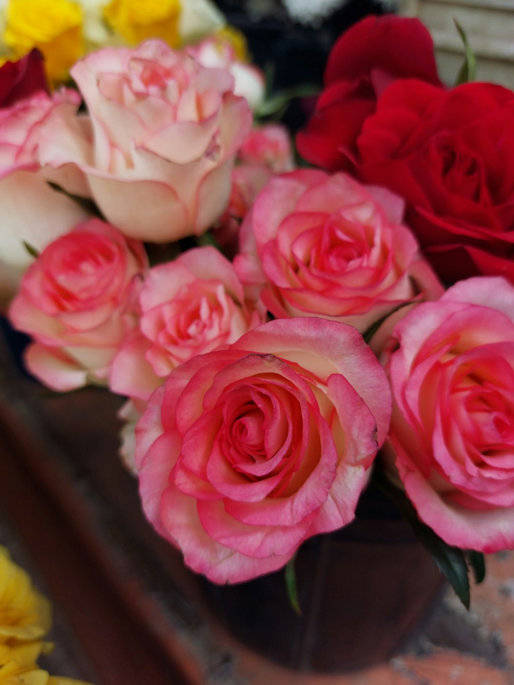 a vase filled with lots of pink and red roses