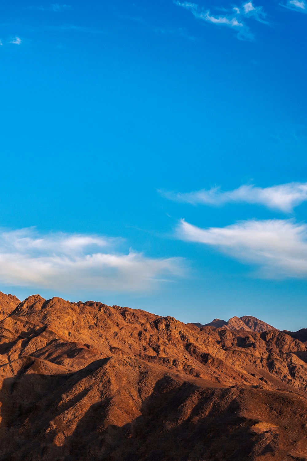 a plane flying over a mountain range under a blue sky