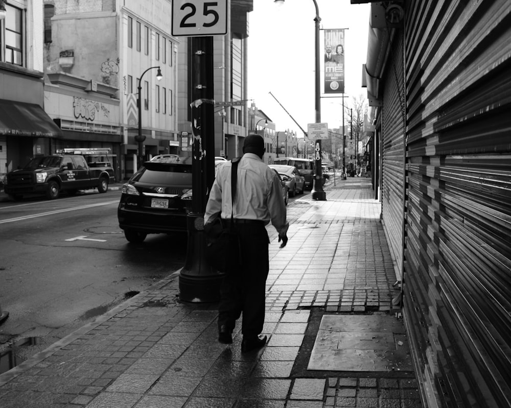 a man walking down a sidewalk next to a street sign