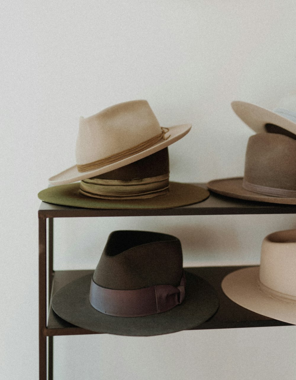 hats are lined up on a shelf against a white wall
