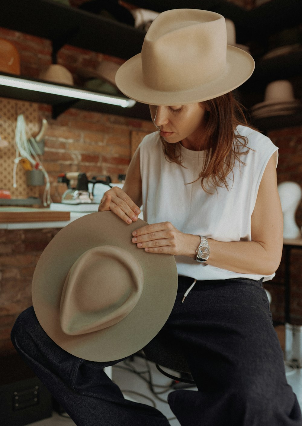 a woman sitting on a chair with a hat on her lap