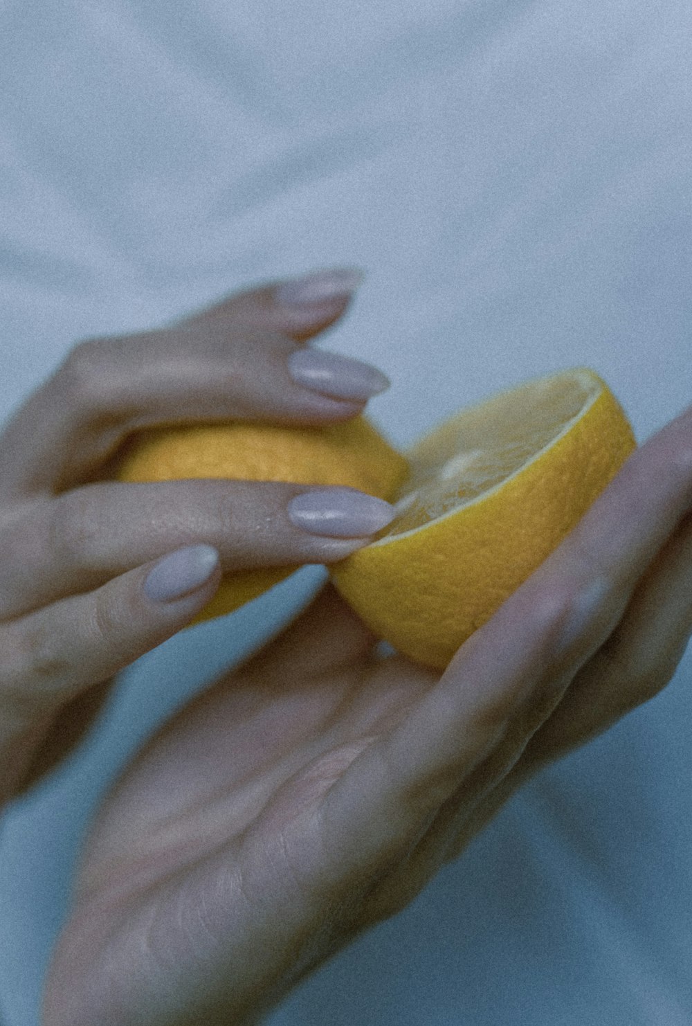 a woman's hands holding a half of a lemon