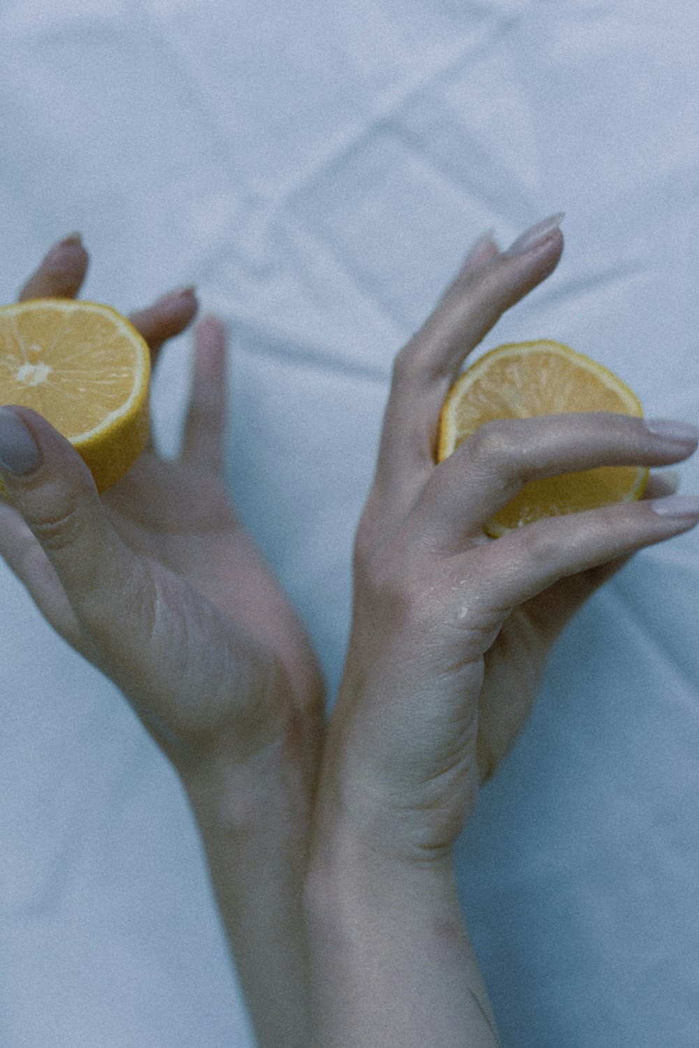 a woman's hands holding a half of an orange