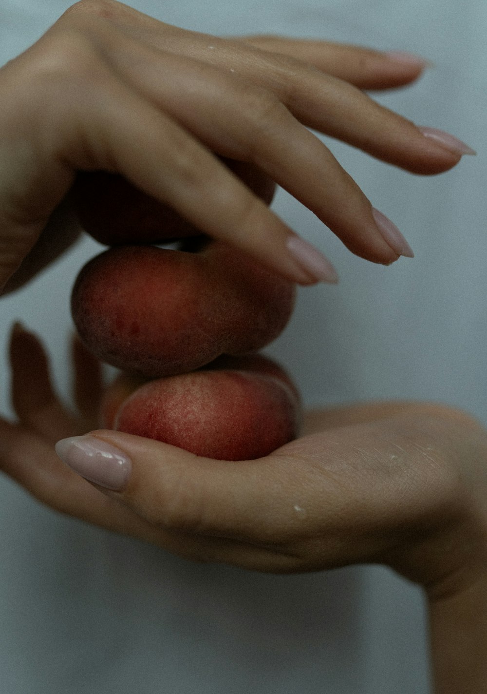 a woman's hands holding three peaches on top of each other