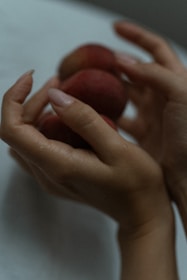Soft, warm image of a woman gently holding fresh fruits symbolizing nutrition and care.
