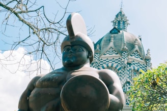 a statue of a man holding a ball in front of a building