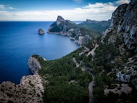 A winding coastal road framed by cliffs and the deep blue sea, perfect for a scenic road trip adventure.