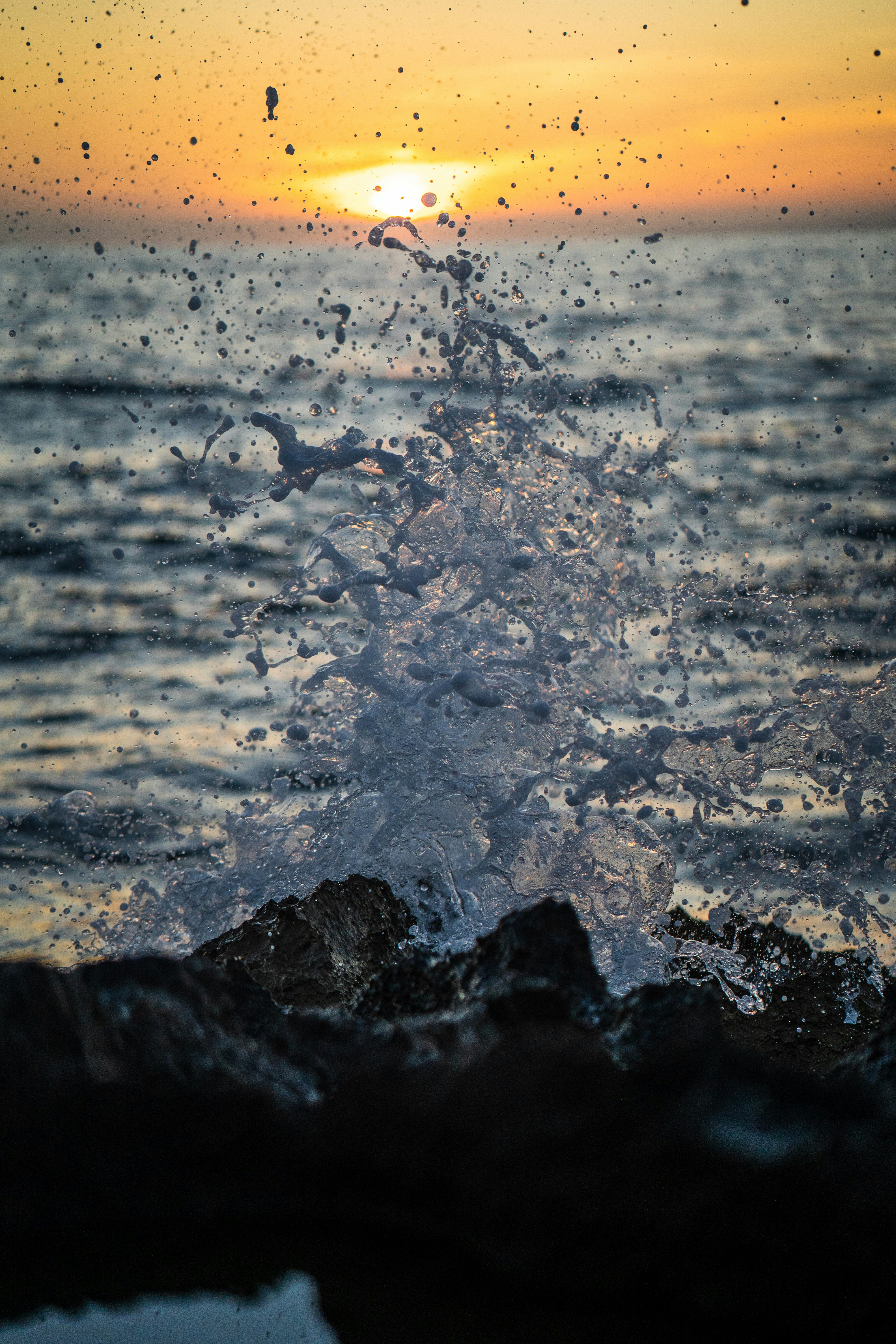 the sun is setting over the ocean and the water is splashing
