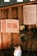 A wooden surface displays a sign with the text 'Free China' in red and white beside a paper listing some requirements or events. In front of the sign, there are white roses and a lit candle in a decorated jar, creating an atmosphere of remembrance or protest.
