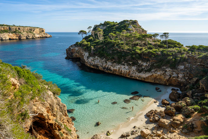 a beach with clear blue water next to a cliff