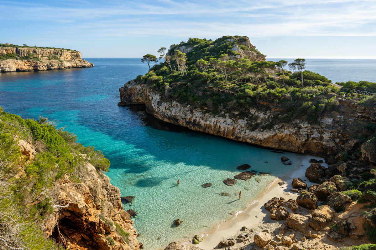 A rocky cove of clear blue water below a cliff