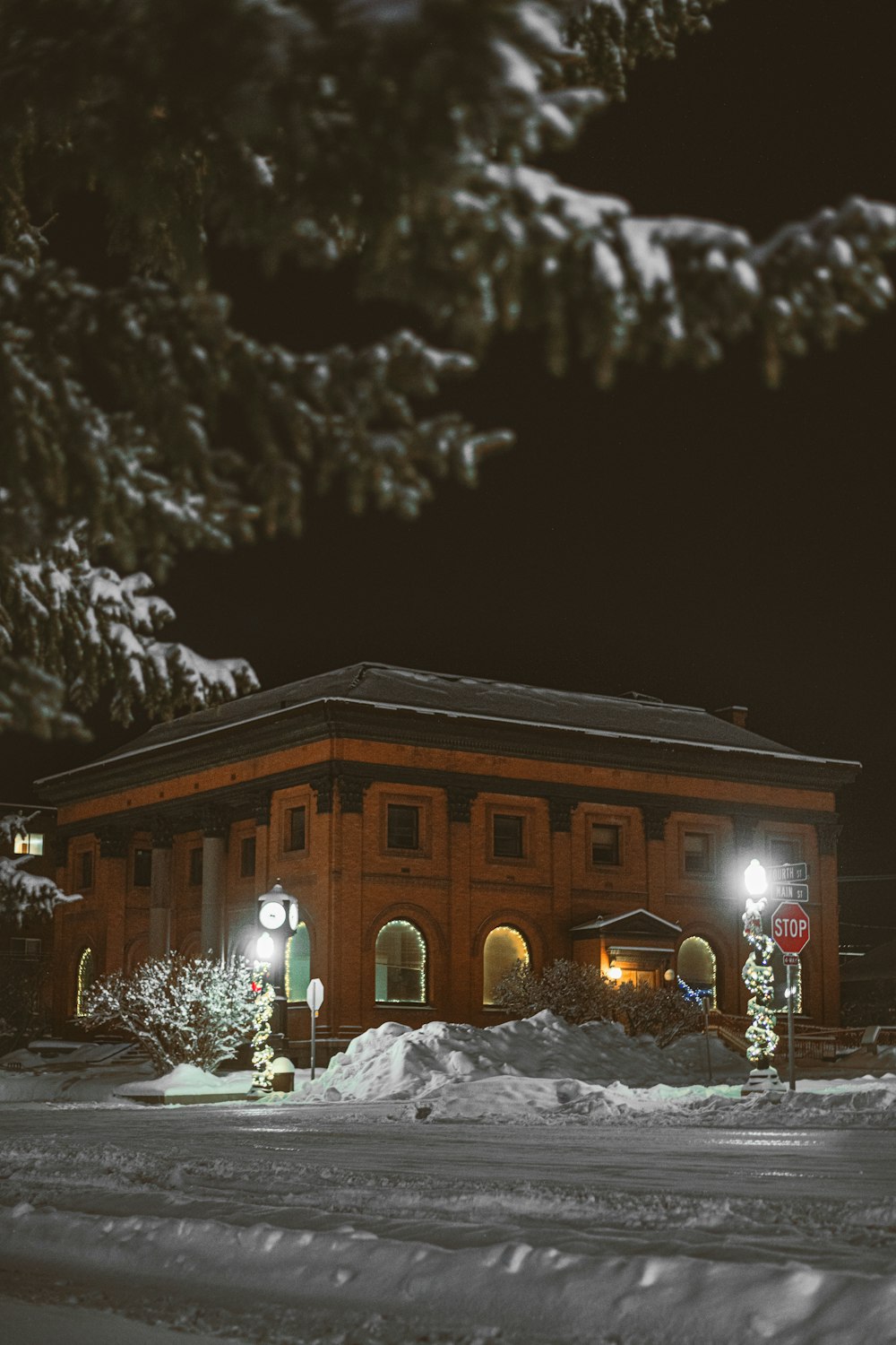 a snow covered street at night with a building in the background