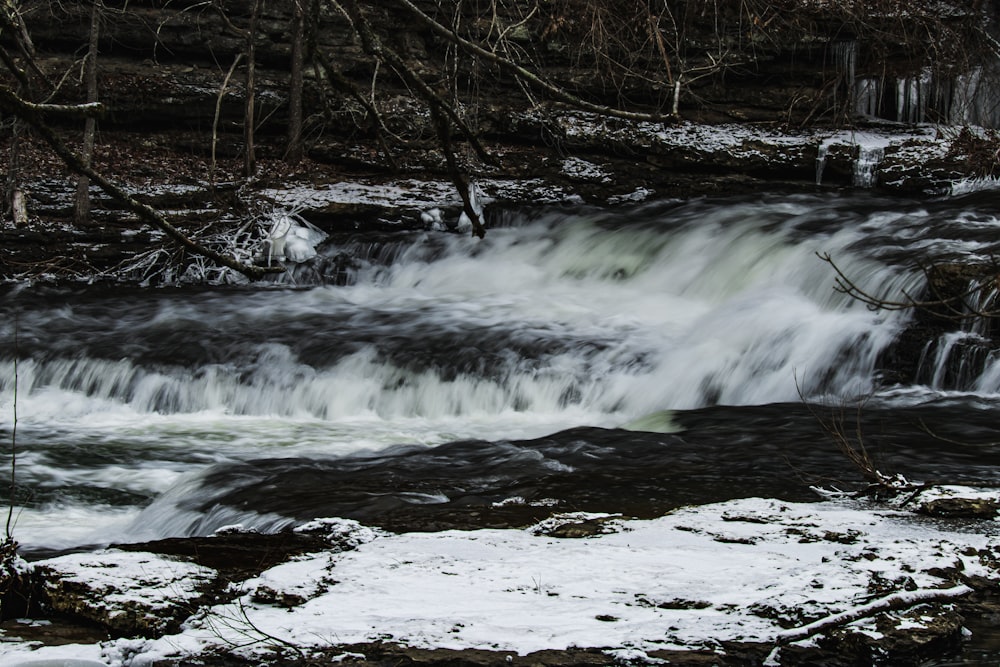 a small waterfall in the middle of a snowy forest