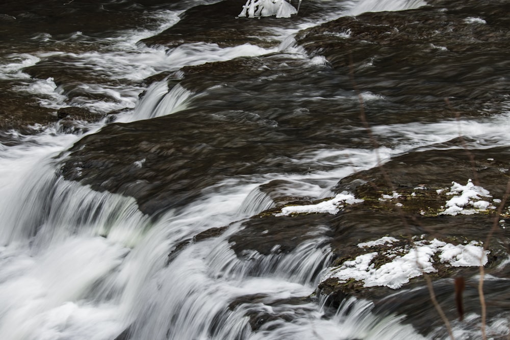 a man standing on a rock next to a waterfall