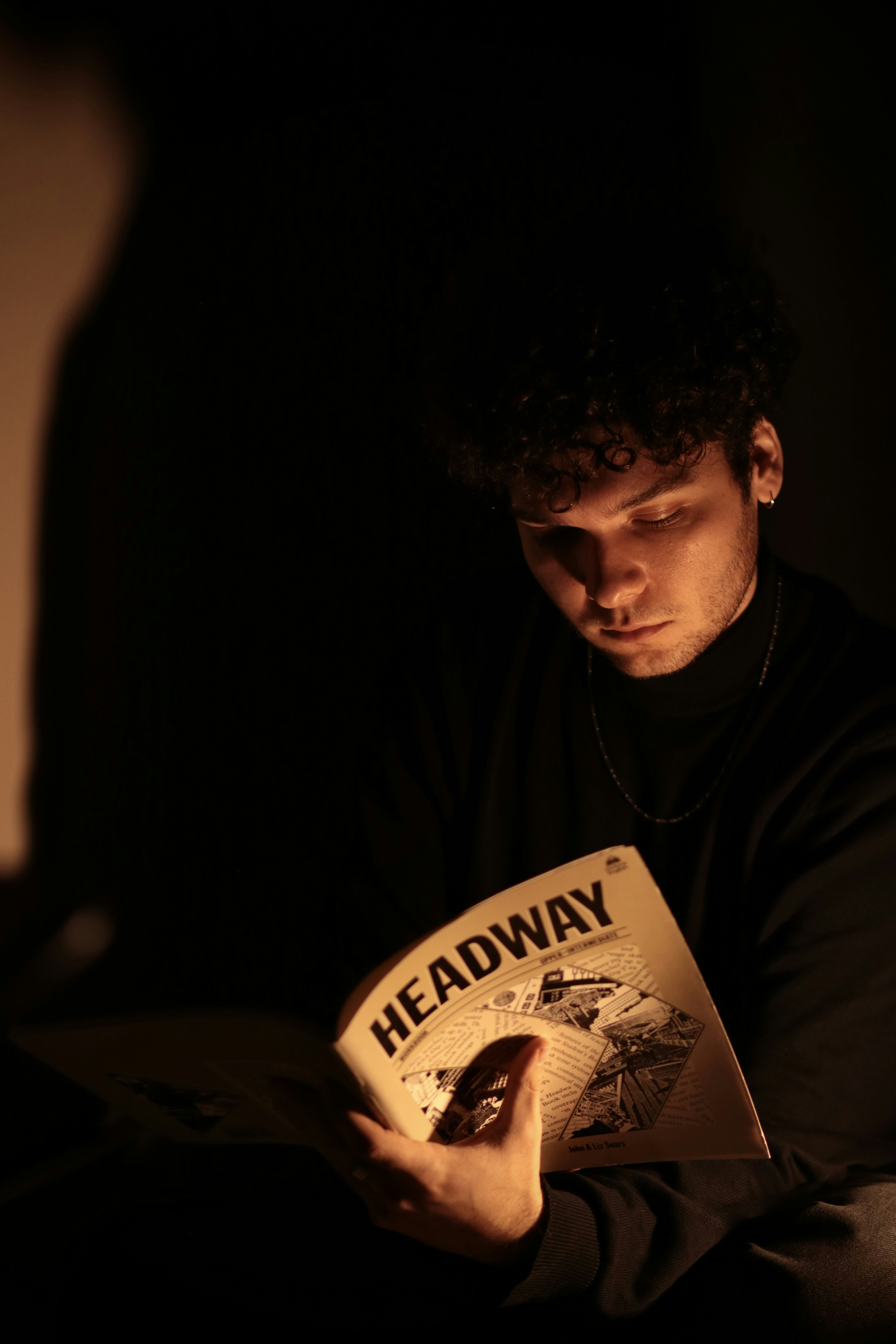 Hombre leyendo un libro en la oscuridad — luz tenue, atmósfera íntima y literaria