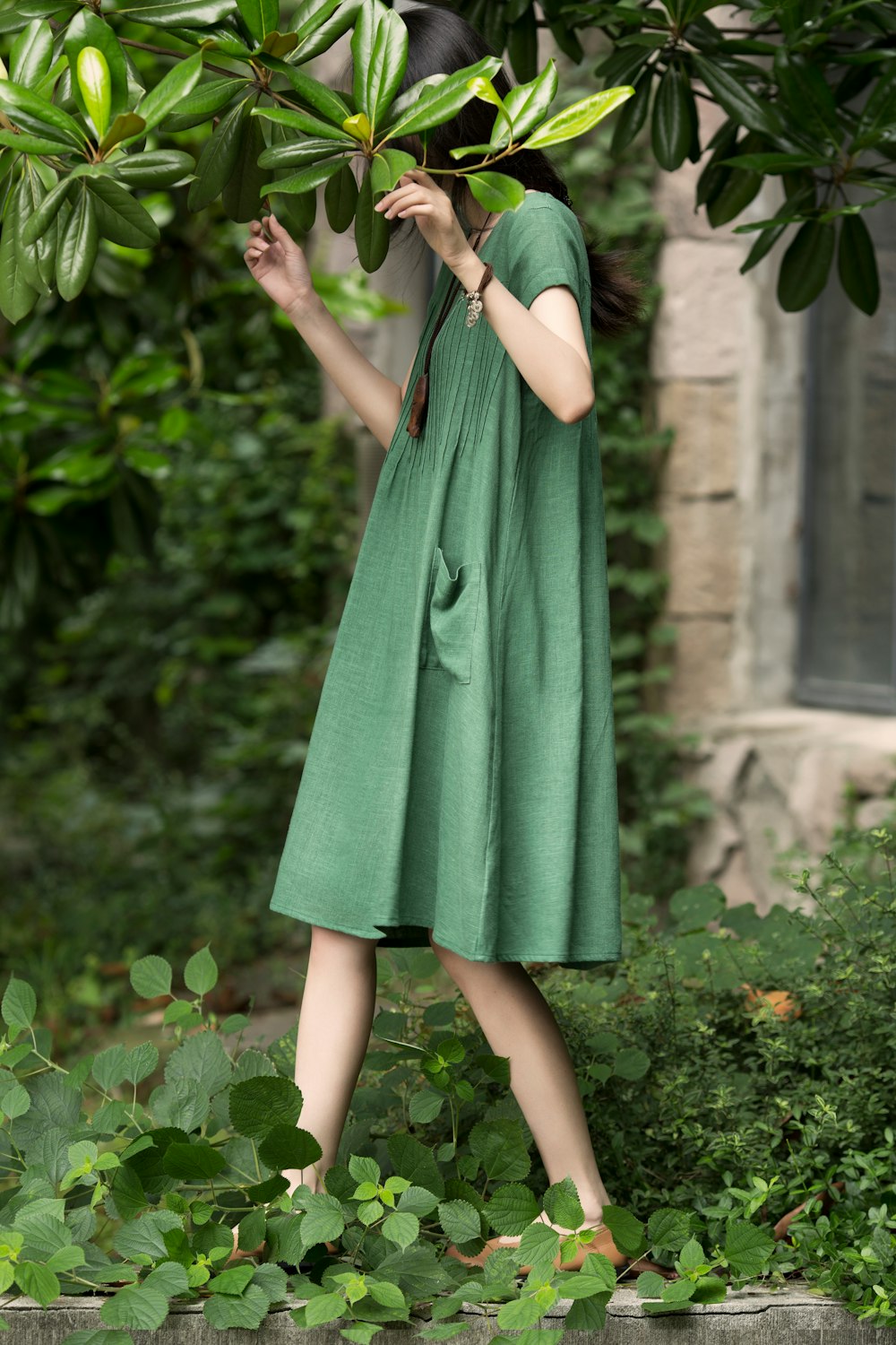 a woman in a green dress standing in a garden