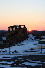 A heavy machinery moving earth on a rural construction site during sunset