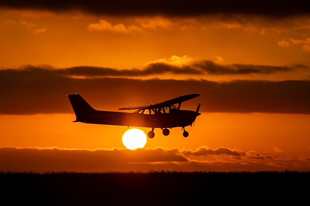 a small plane flying in the sky at sunset