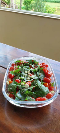 Close-up of a colorful bowl of fresh summer salad with cherry tomatoes and herbs.