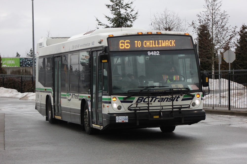 a bus driving down a street next to a fence