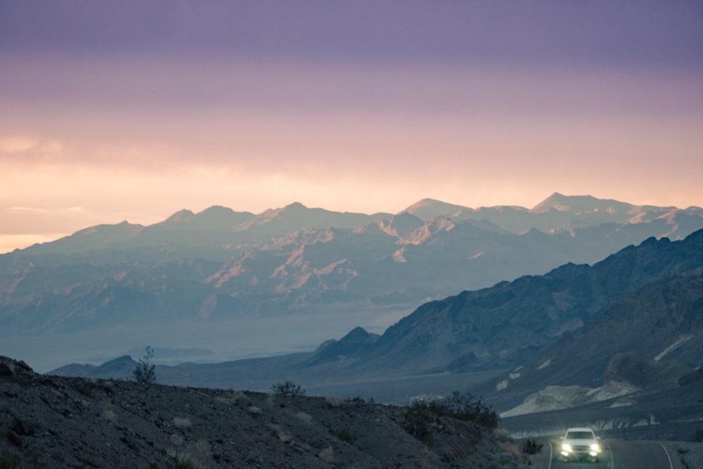 a car driving down a road with mountains in the background