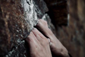 Close-up of hands gripping a textured rock during a challenging vertical climb