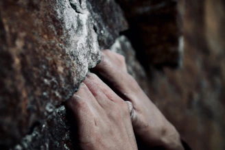 Close-up of hands gripping textured rock during an outdoor climbing session.