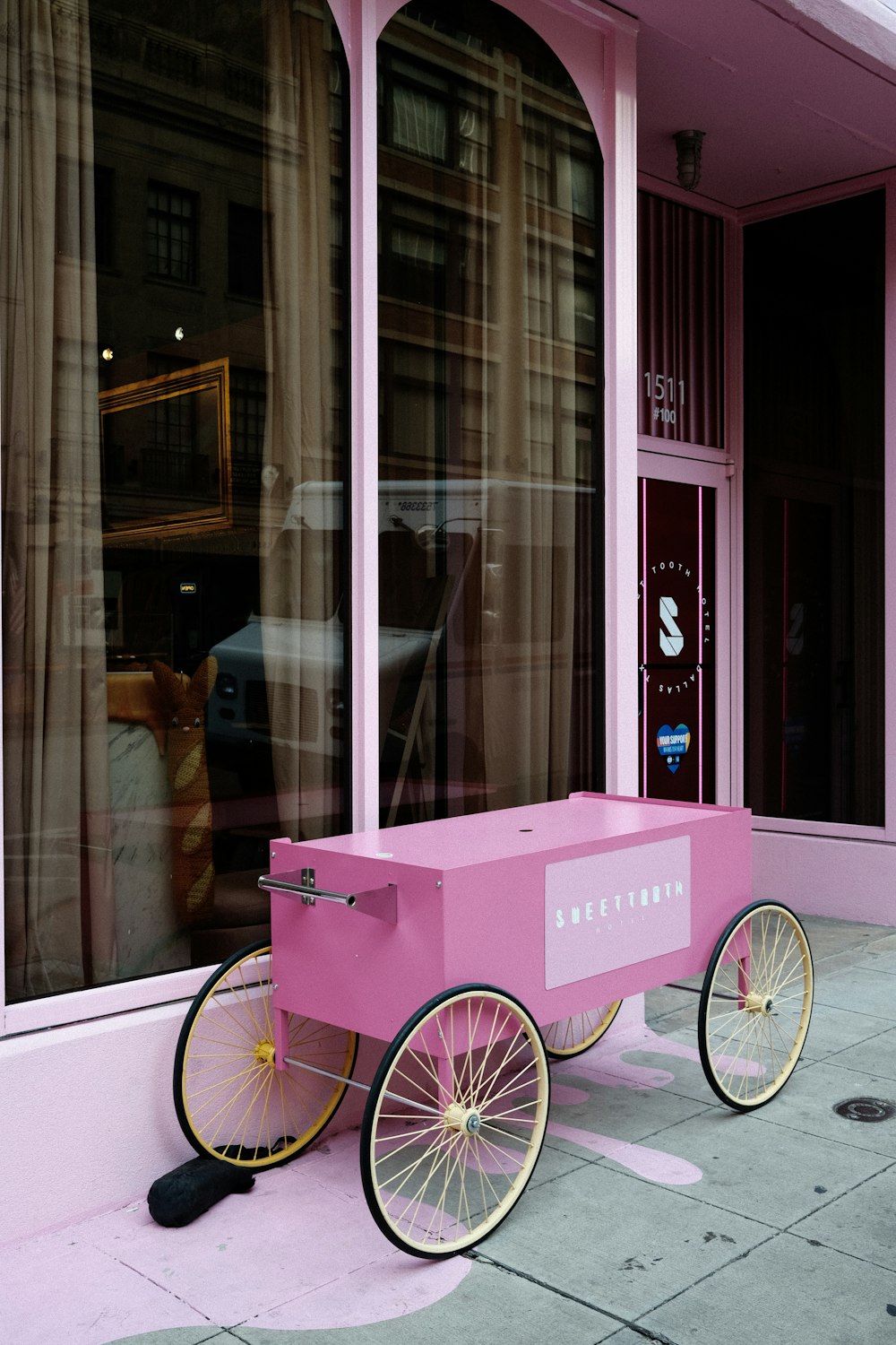 a pink cart sitting on the side of a street