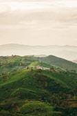 a hill covered in lush green hills under a cloudy sky