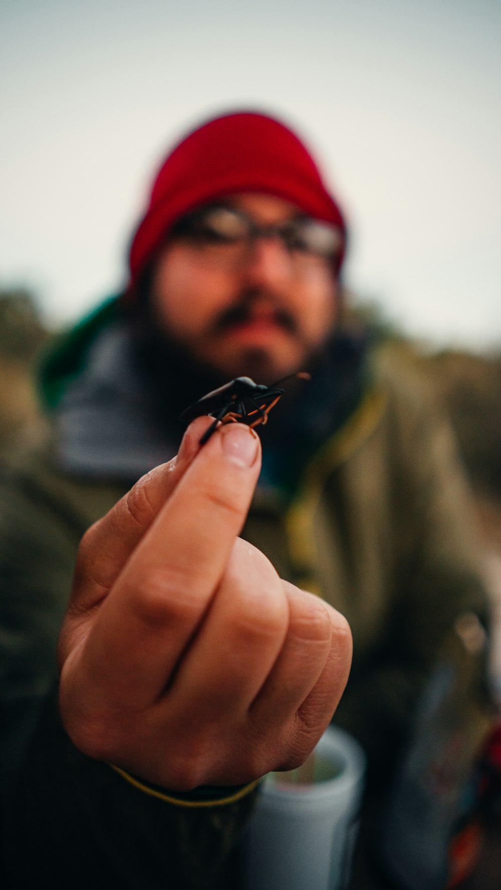 a man holding a tiny black insect in his right hand