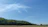 A wide RV site surrounded by lush greenery under a clear blue sky.