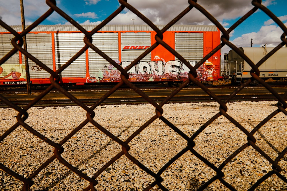 a train on a track behind a chain link fence