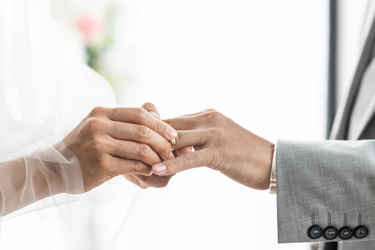 Dua tangan saling menggenggam saat cincin dipasangkan di jari.