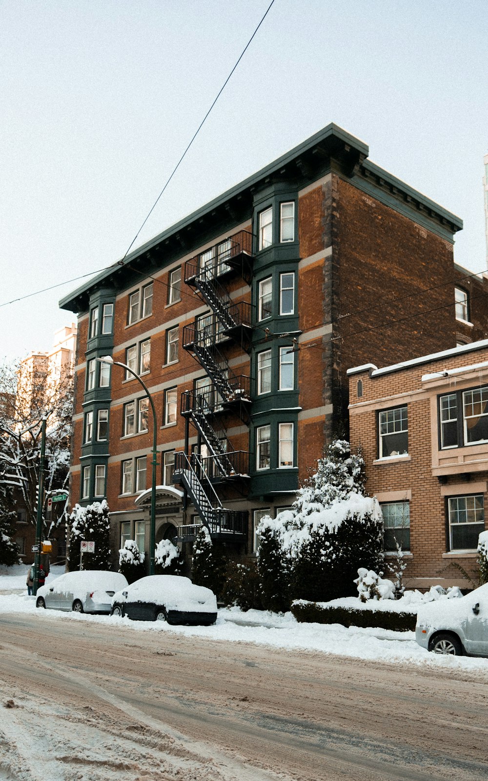 a snow covered street with cars parked on the side of the road