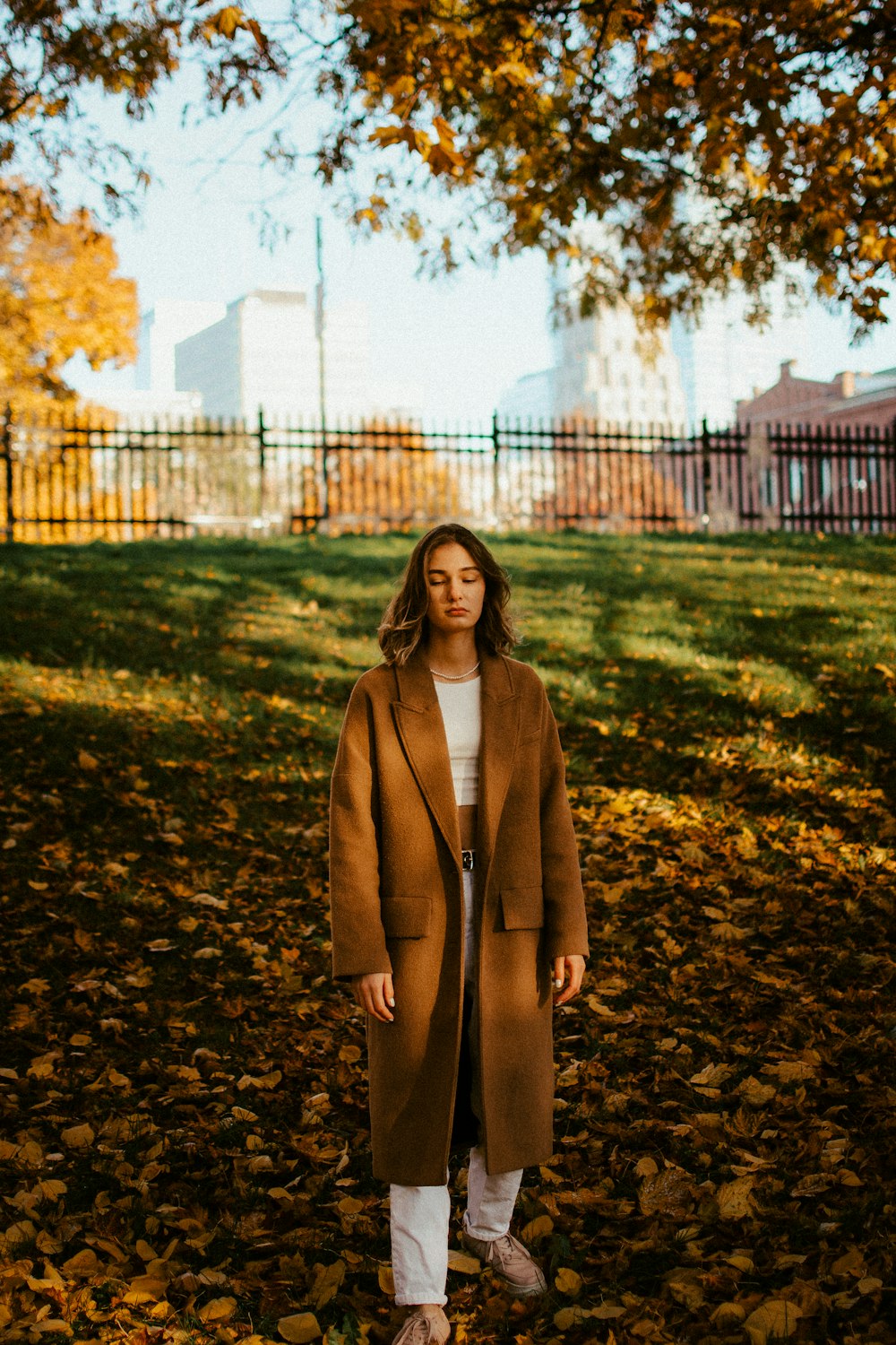 a woman standing in the leaves in a park