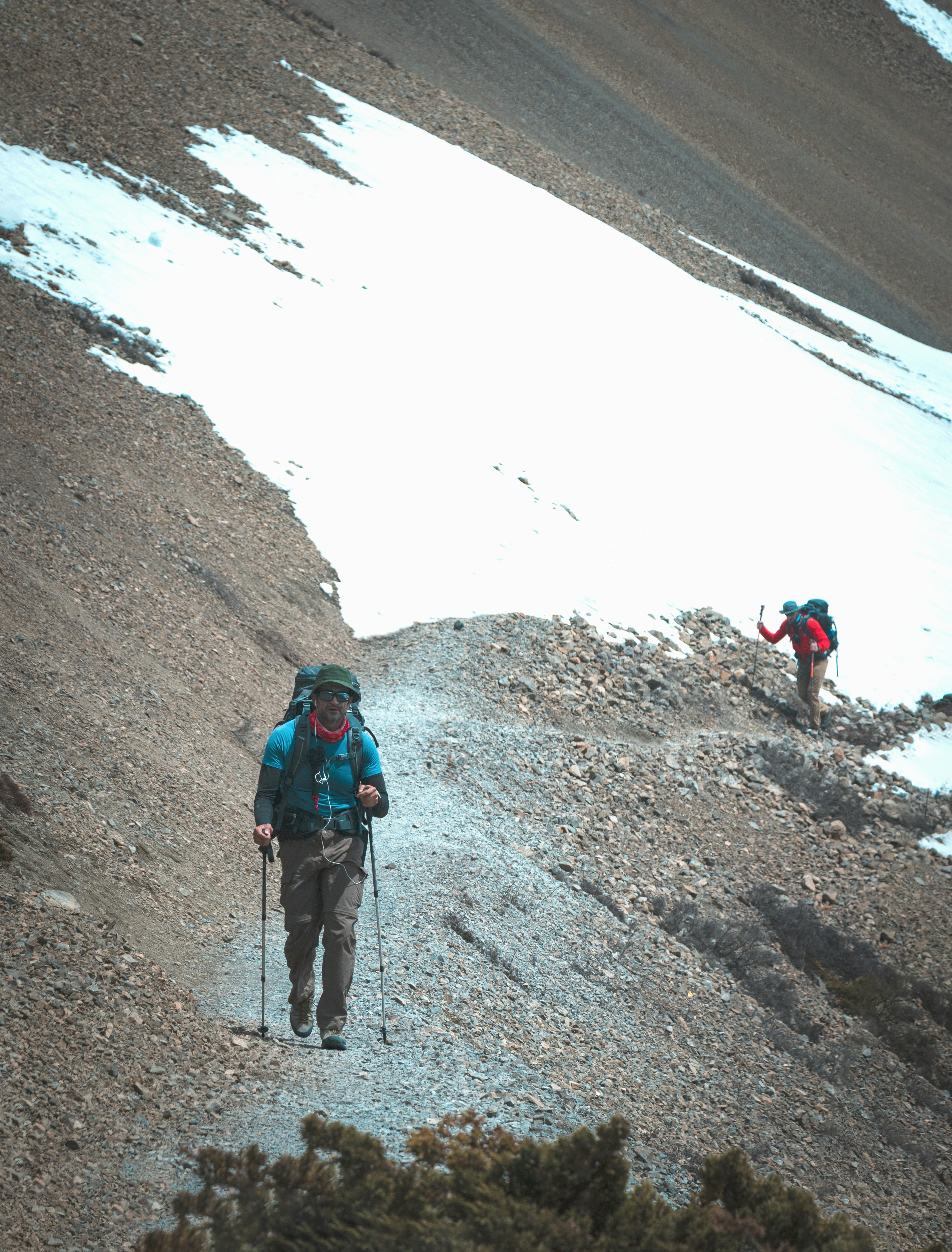 a couple of people walking up a snow covered hill