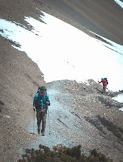 a couple of people walking up a snow covered hill