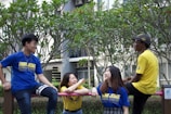 A group of friends wearing matching Roy Tshirts, laughing outdoors.