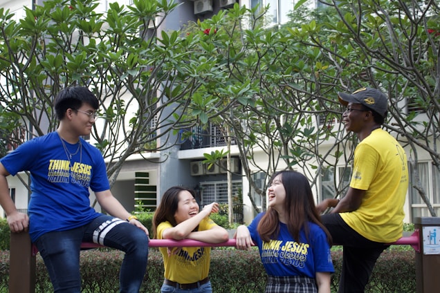 A diverse group of people wearing colorful graphic tees in an urban park setting, enjoying their time together.