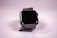 Close-up of a sleek noir smartwatch glowing softly against a pitch-black background.