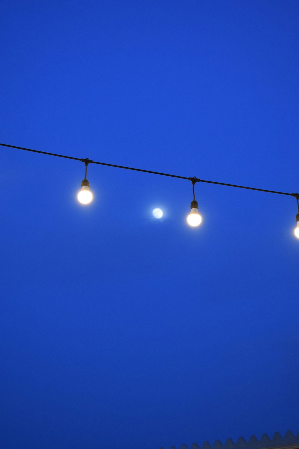 a row of lights hanging from a wire against a blue sky