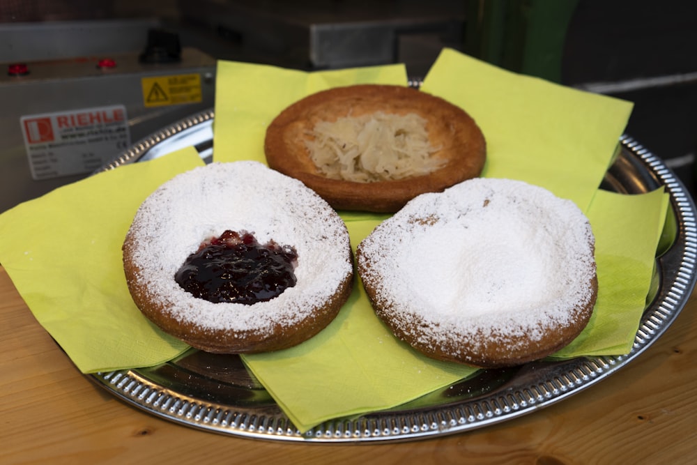 three donuts covered in powdered sugar on a plate