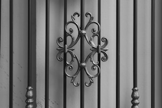 Intricate wrought iron details are set against vertical bars, featuring ornate scrollwork in a symmetrical design.